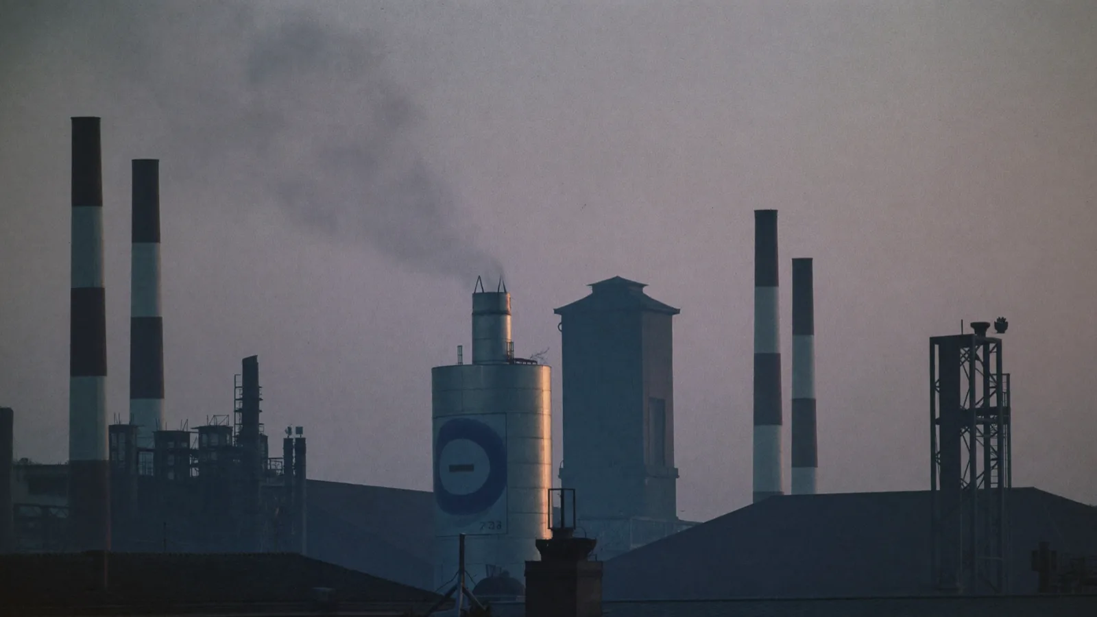 Ciminiere e silos industriali in controluce all alba