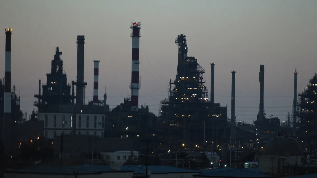 Skyline industriale al crepuscolo con ciminiere e impianti illuminati