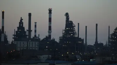 Skyline industriale al crepuscolo con ciminiere e impianti illuminati